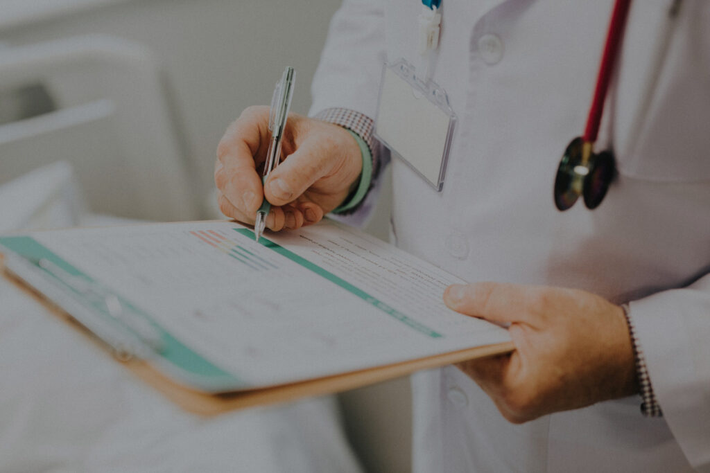 Doctor with stethoscope writing patient chart