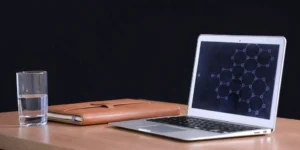 Pharmaceutical regulatory affairs tools: Laptop, notebook, and water glass.
