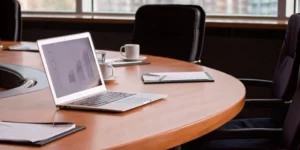 Laptop displaying a performance chart with documents during a management review meeting.