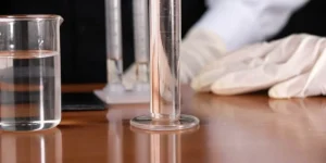 A gloved hand performs a swab test on lab equipment for a cleaning validation protocol.