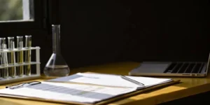 A periodic safety update report (PSUR) on a desk with a laptop and scientific equipment.