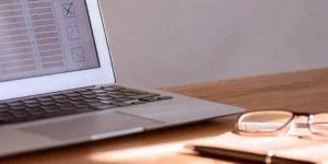 A 21 CFR Part 11 compliance checklist on a laptop screen, with glasses and a pen on the desk.