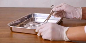 Gloved hands handling reusable medical devices for reprocessing.