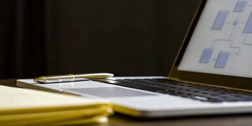 Planning SOP development services with a laptop flowchart, notepad, and pen.