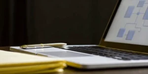 Planning SOP development services with a laptop flowchart, notepad, and pen.