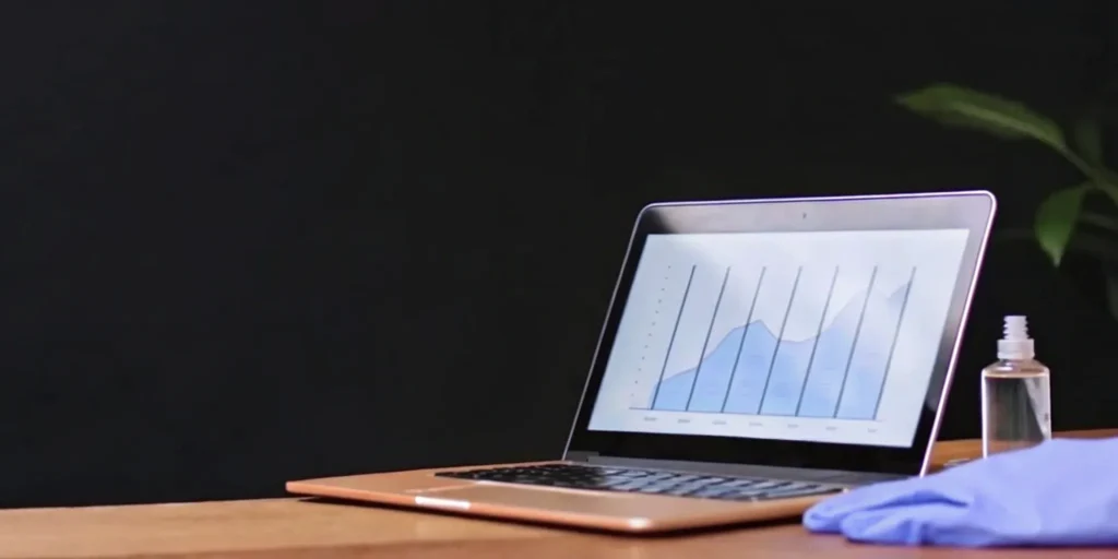 Laptop displaying chart beside gloves and sanitizer