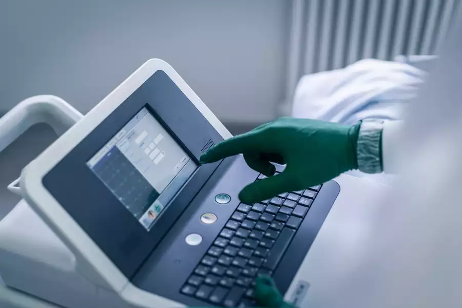 A worker in PPE using an ECG machine.