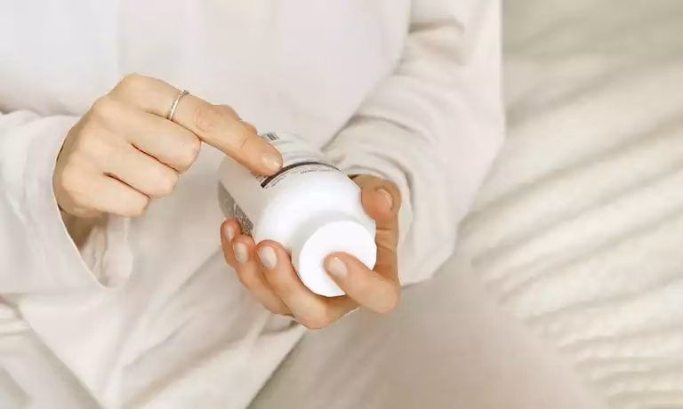 A person looking at a supplement bottle for information