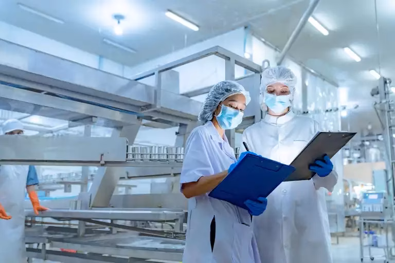 Food safety personnel wearing protective gear while working on production line